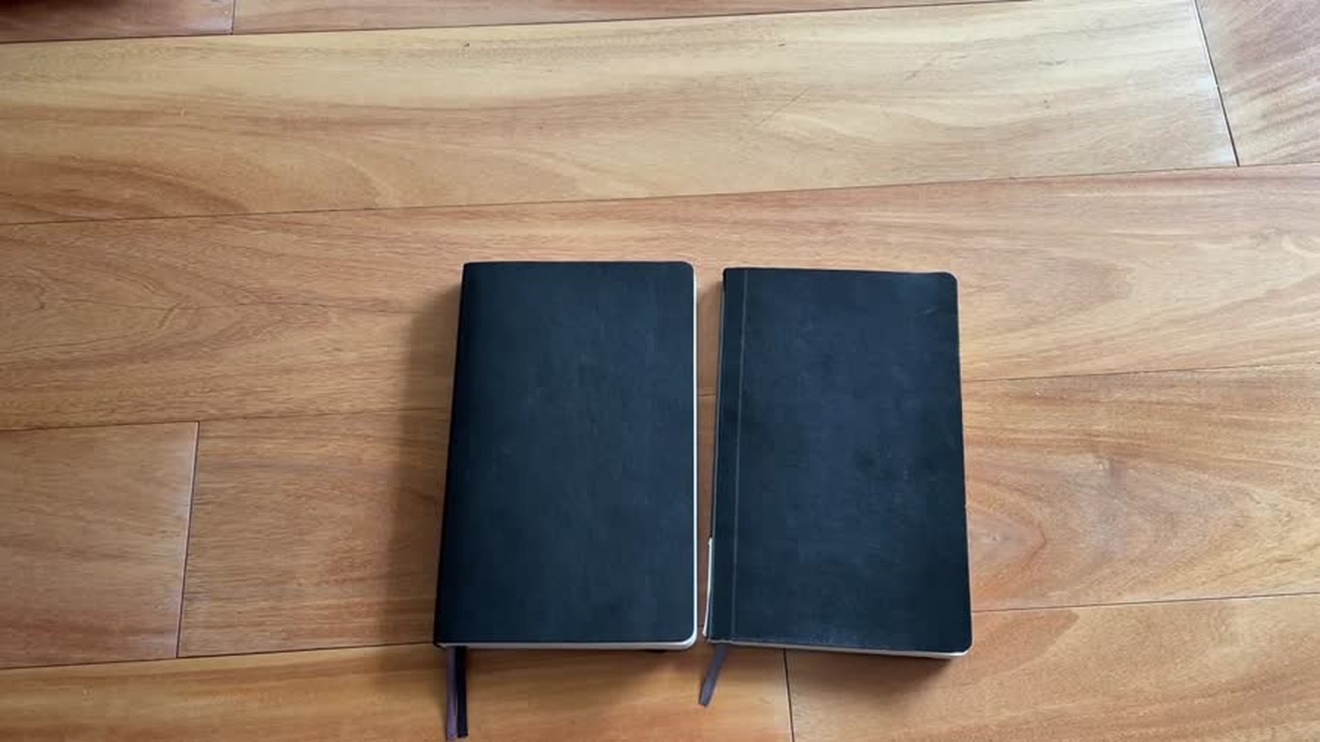 Old and new Moleskine soft cover notebooks side by side on a wooden desk
