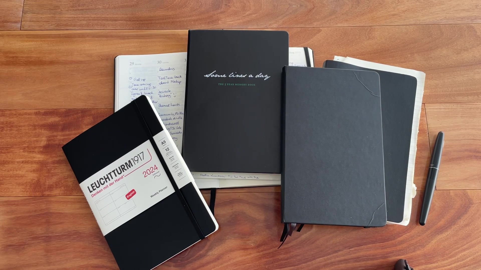 Which Planner Am I Using? My Planner Journey 1 Planner journey overview with several notebooks and planners on a wooden desk