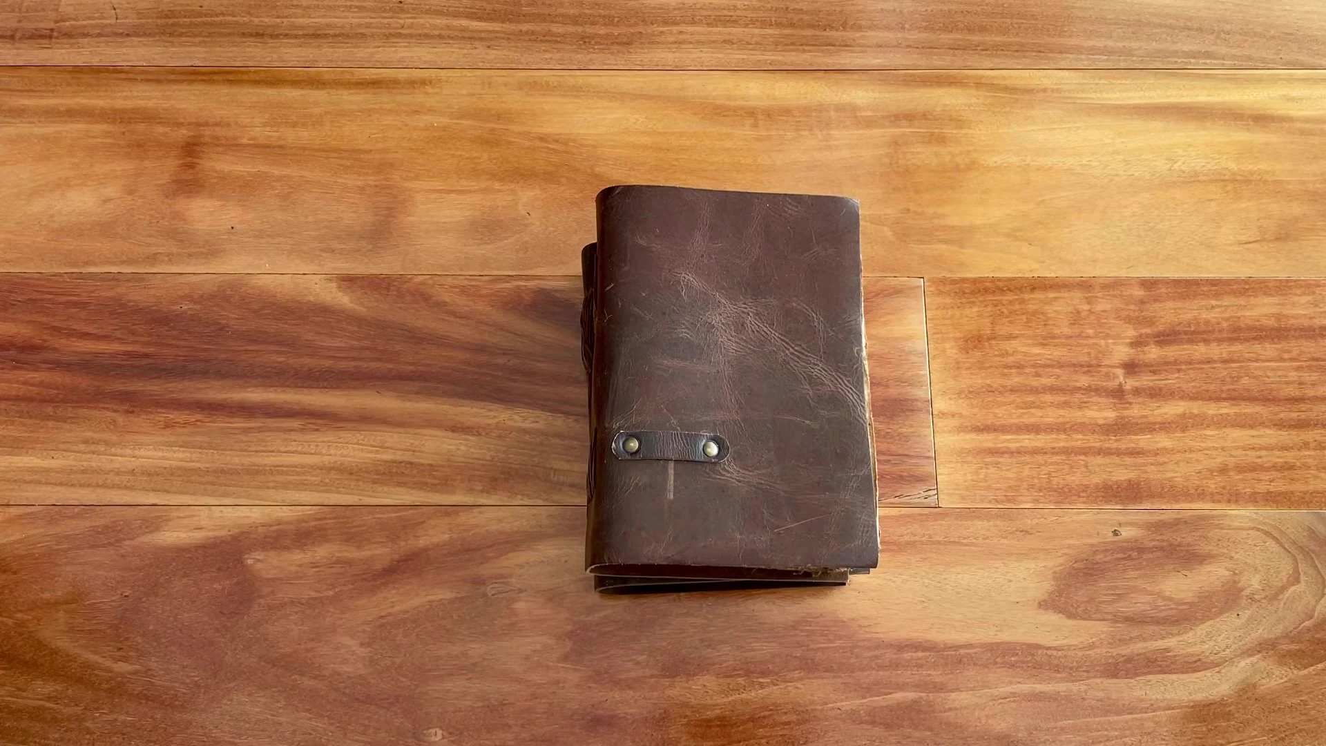 Vintage Feel Notebooks and Journals 2 A closed vintage leather journal with a metal clasp on a wooden desk
