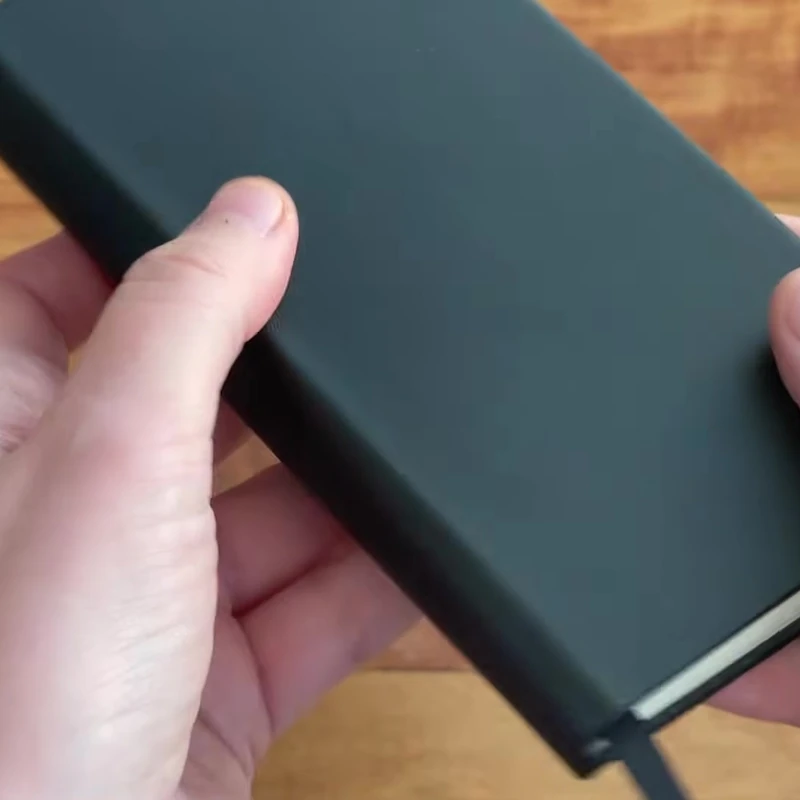 Writersblok pocket notebook held above a wooden desk